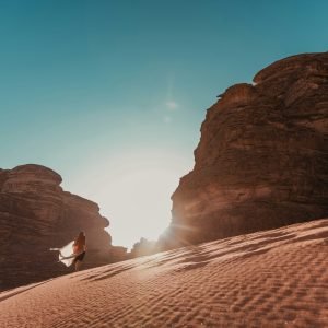 a person standing in the sand near some rocks