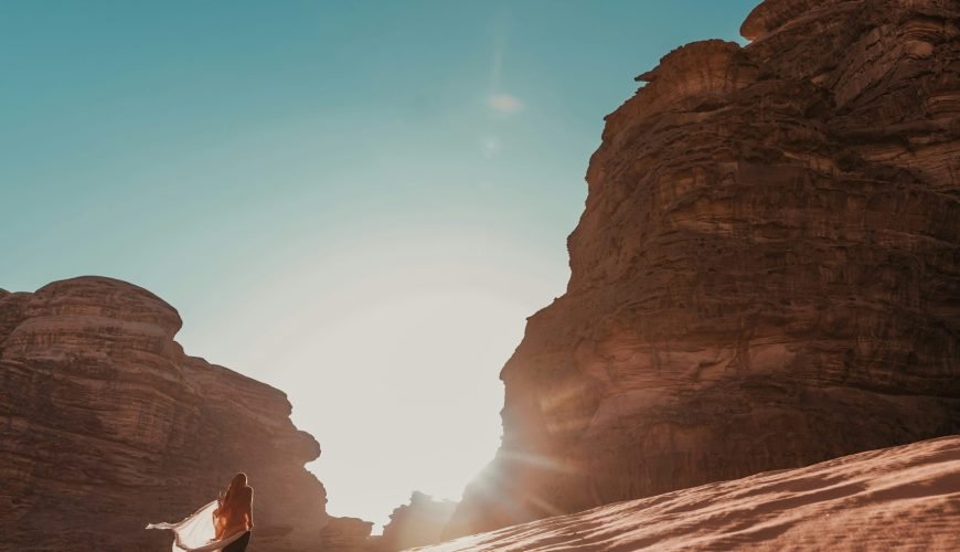 a person standing in the sand near some rocks